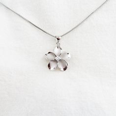 Introducing our exquisite Silver Plumeria Flower Necklace, a stunning piece that encapsulates the beauty of nature. This captivating necklace features a meticulously crafted Plumeria flower pendant adorned with sparkling Cubic Zirconia, adding a touch of brilliance to your look. The silver finish exudes elegance and sophistication, making it a perfect accessory for any occasion. The necklace comes with an 18-inch Rhodium Plated Box Chain, ensuring a comfortable and secure fit. Rhodium plating pr White Gold Flower Shaped Necklace, White Gold Flower Charm Necklace, Nickel-free Flower Pendant Jewelry For Mom, Silver Flower Necklace For Anniversary, Nickel-free Flower Pendant Jewelry Gift For Mom, White Gold Sterling Silver Flower Necklace, Silver Flower Pendant Necklace For Mother's Day, Silver Flower Necklace For Mom, Silver Flower Necklace Gift For Mom