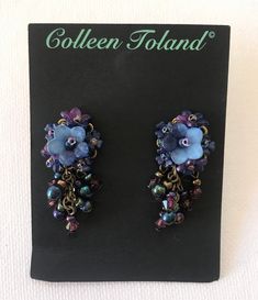 Lovely Navy Blue Flower Earring. A single larger flower on top of the ear, surrounded by dainty small flowers in a purple hue and finished with several drop beads in Aurora Borealis colors (rainbow blue). The flowers are hand colored by me and they are hand beaded together with glass seed beads. A pretty earring that's very wearable for day time. Matching jewelry listed below. This is a quality piece of jewelry that will last a life time. Created by designer Colleen Toland who has been creating Elegant Flower-shaped Earrings With Dangling Beads, Adjustable Blue Flower Beaded Earrings, Adjustable Flower Shaped Blue Beaded Earrings, Elegant Blue Flower Charm Earrings, Bohemian Blue Jewelry With Handmade Flowers, Elegant Lavender Beaded Earrings, Blue Bohemian Flower Earrings, Blue Handmade Flower Drop Earrings, Purple Flower Jewelry With Handmade Details