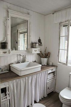 a bathroom with a sink, toilet and vanity in it's center area next to a window