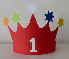 a red paper crown with stars on it and the number one painted on it's side