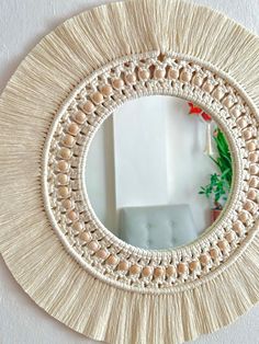 a round mirror hanging on the wall next to a white chair and potted plant