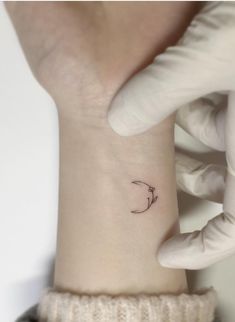 a person with a small tattoo on their left wrist and the moon behind her arm