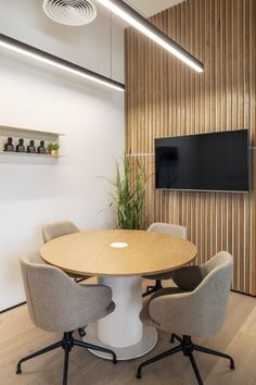 a round table with four chairs and a flat screen tv mounted on the wall behind it