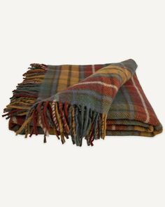 two plaid throw blankets folded on top of each other, one with fringes and the other with tassels