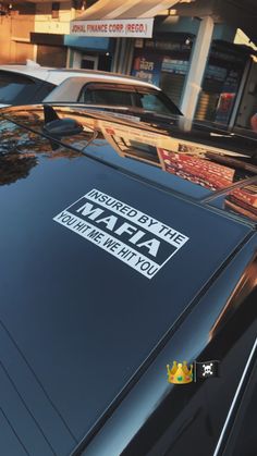 a black car parked in front of a building with a crown on it's hood