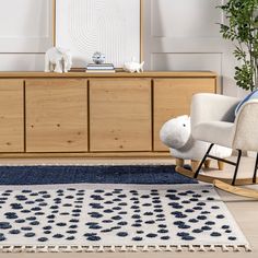 a white rocking chair sitting on top of a blue rug next to a wooden dresser