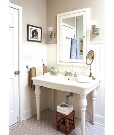 a white sink sitting under a bathroom mirror next to a doorway with pictures on the wall