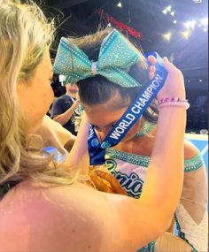 a woman wearing a blue ribbon around her head and holding onto another woman's hair