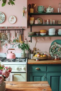 a kitchen filled with lots of green and pink decor on the wall above an oven