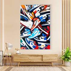 an abstract painting on the wall in a living room with a wooden table and plant