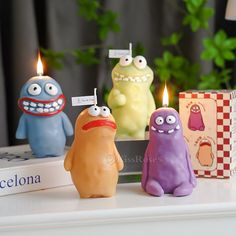 three small candles with faces on them sitting next to each other in front of a book