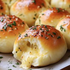 rolls with cheese and chives on top of them are sitting on a white plate