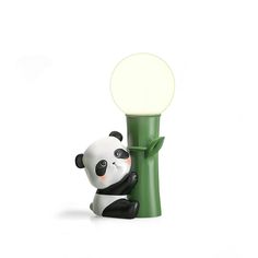 a small toy panda bear sitting on top of a green pole next to a light