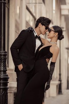 a man in a tuxedo kissing a woman on the cheek while standing next to a lamp post