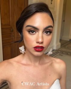 a woman in a white dress with red lipstick and flowers on her hair is posing for the camera