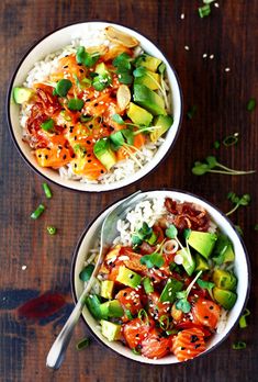 two bowls filled with rice and vegetables on top of a wooden table