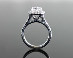 a close up view of a diamond ring on a reflective surface