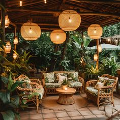 an outdoor seating area with wicker furniture and hanging lights, surrounded by greenery