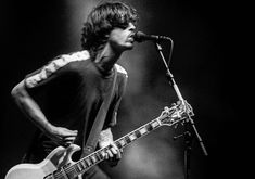 a man with a guitar standing in front of a microphone