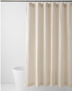 a white shower curtain hanging on the side of a bath tub