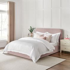 a bed with white sheets and pillows on top of it in a bedroom next to a window