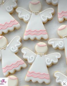 decorated cookies in the shape of angel wings on a table with white frosting and pink accents