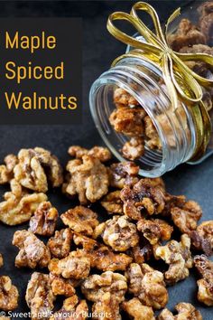 maple spiced walnuts in a glass jar on a black surface with the words maple spiced walnuts