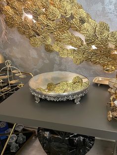 a silver bowl sitting on top of a table next to a mirror and other items