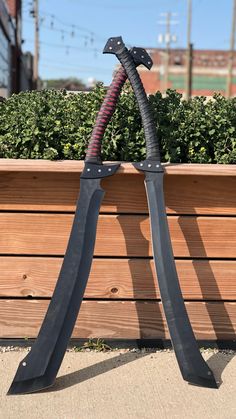 a large pair of scissors sitting on top of a planter next to a wooden fence