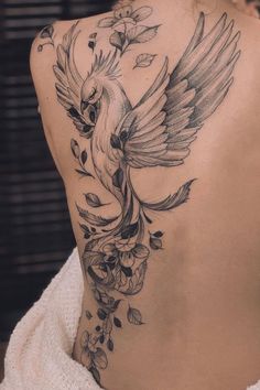 a woman's back with a bird tattoo on it