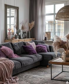 a living room filled with lots of furniture and pillows on top of a rug next to a window