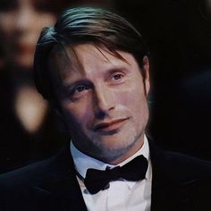 a man in a tuxedo and bow tie looking at the camera with an intense look on his face