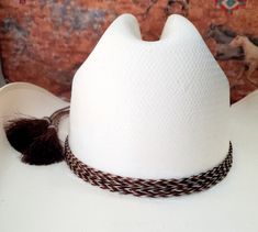 Braided Horse Hair Adjustable Hatband has extra long braided ends and sliding knot with 2 horse hair tassels.  These stunning hat bands are made from genuine braided horse hair and will compliment your favorite cowboy hat.   - Incudes 2 horse hair tassels that measure 3" long - Horsehair Cowboy hatband is made with exception quality horse hair - This hat band will wrap 4 braided strands around the crown of the hat to create a gorgeous 4 strand braid. - Hand crafted, genuine horse hair See my other horse hair hatbands:  https://www.etsy.com/shop/BlueEyesDesignsHB?ref=shop-header-name&listing_id=1512779935&from_page=listing&section_id=50325232 See my other listings which include hairpipe hatbands:   https://www.etsy.com/shop/BlueEyesDesignsHB?ref=shop-header-name&listing_id=1476946144&sectio White Adjustable Hat For Country Events, Adjustable White Hat Bands For Western Events, Adjustable White Hat Band For Country Events, Traditional White Hat For Rodeo, Handmade White Country Style Hat Band, Country Style White Hat Bands For Festival, Handmade White Country Hat Band, Traditional White Hat For Festival, Traditional White Hat Bands For Festival