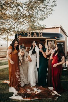 a group of women standing next to each other in front of a food truck at a wedding