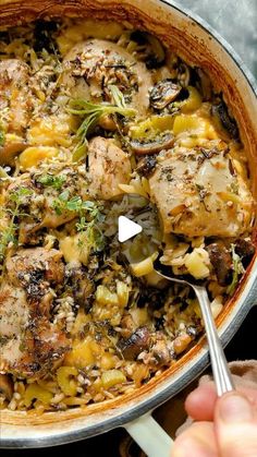 a pan filled with chicken and vegetables on top of a stove next to a person holding a spoon