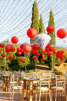 tables and chairs with red lanterns hanging from the ceiling