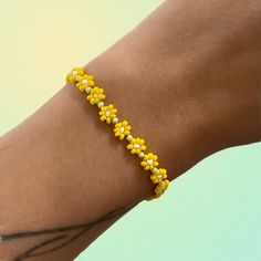 a woman's arm with a yellow bracelet on top of her left arm and the wrist is made out of beads