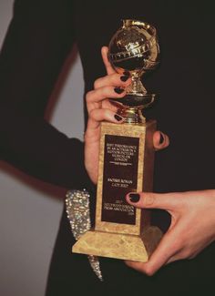 a woman holding up an award in her right hand and the other hand on top of it