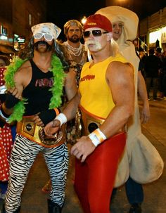 two men in costumes standing next to each other on the street with people dressed up