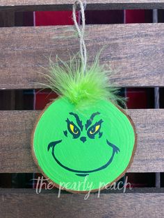 the grin face painted on a piece of wood is hanging from a string with green hair