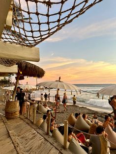 many people are relaxing on the beach at sunset