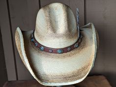 The Cassidy starts with a soft palm hat body that has been flame distressed so it looks like it has already been broken in. The brim is approximately 4" and the crown is 5". There is a wire in the brim so you can shape it however you want. The leather hatband is new rein leather and has lots of Southwestern Conchos. The back of the band has a deer antler bead for accent. Stampede strings are attached to hat which will make it a great hat for riding or on those windy days. Finished with an Owl fe Rustic Adjustable Short Brim Hat, High Crown Hats For Summer Rodeo, Rustic Fitted Hats For The Beach, Rustic Adjustable Brimmed Hat, Rustic Fitted Beach Hat, Adjustable Distressed Brimmed Hat, Rustic Adjustable Fedora With Flat Crown, Western Style High Crown Hat For Summer, Western Style High Crown Summer Hat