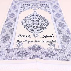 an islamic prayer mat with arabic writing on the front and bottom corner, which is decorated in blue and white