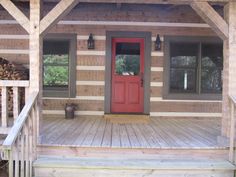 the front porch of a log cabin with red door