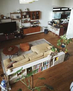 a living room filled with furniture and a book shelf next to a tv on top of a hard wood floor