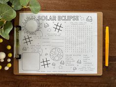 an open notebook with the words solar eclipse on it next to some plants and pencils