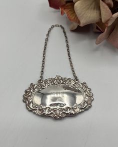 an antique silver serving dish on a chain with flowers in the background