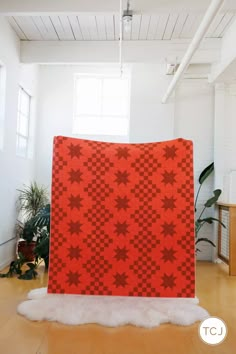 a large red blanket sitting on top of a wooden floor