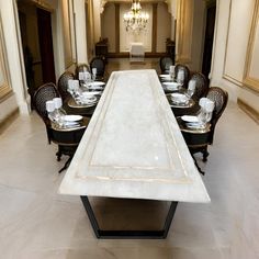 a long dining table with white marble top in a large room filled with tables and chairs