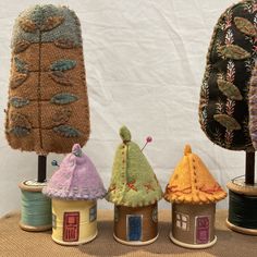 three small houses made out of yarn sitting on top of a table